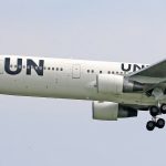 Close-up of a United Nations airplane in flight, showing detailed landing gear.